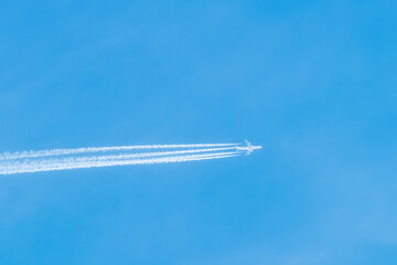 Shot of a jet plane high in the blue skies. Airliner in the blue sky leaves air trails. Travelling...