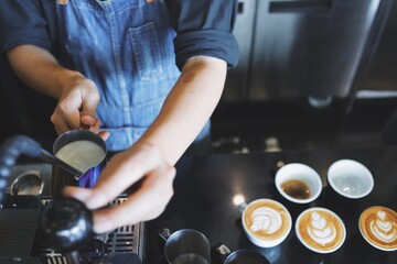 Barista making coffee latte art in cafe.