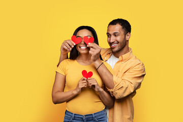 Glad millennial african american male puts hearts to eyes of wife, have fun