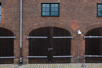 Front exterior view of typical old brick building with wooden arch gate entrance for garage along waterside of Copenhagen, Denmark. 