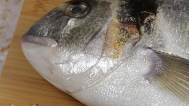  daurade enti&egrave;re, en gros plan, sur une planche &agrave; d&eacute;couper