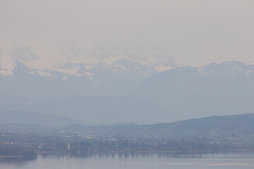 Fototapeta na wymiar A lake in the canton of Aargau called Hallwilersee and the snow-covered Alps in the background.