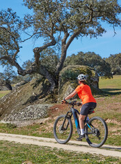 nice senior woman cyling with her electric mountain bike in a stone oak forest of the Extremadura department of Spain