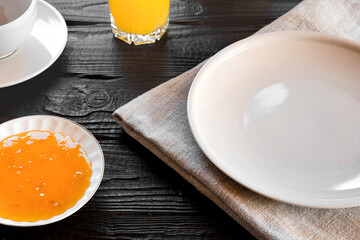 White empty plate mock up on wooden table. Coffee cup, jam, orange juice on a rustic dark background. Food mockup. Empty dish template. Continental breakfast. Close up view. Good morning copy space