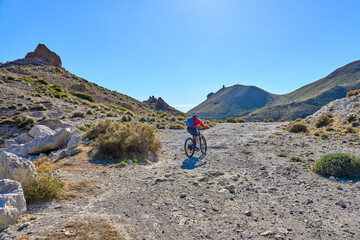 Fototapeta premium nice senior woman cycling with her electric mountain bike in the volcanic nature park of Cabo de Gata, Costa del Sol, Andalusia, Spain