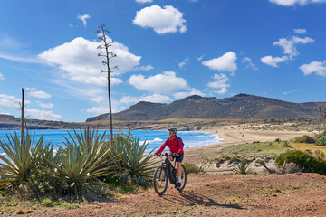 nice senior woman cycling with her electric mountain bike in the volcanic nature park of Cabo de...