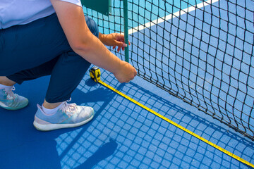 Tennis referee checks the parameters of the tennis net before the start of the match