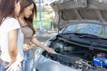 Two Asian people try to check the car engine and wait for assistance after a car breakdown on street. Concept of a vehicle engine problem or accident and emergency help from a Professional mechanic