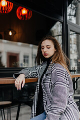 A woman sits on a bench wearing a grey sweater and jeans