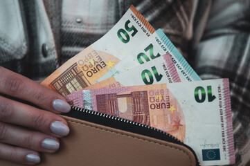 Woman holding wallet with euro money.
