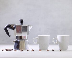 Metal geyser coffee maker on table with cup