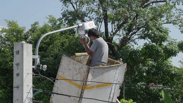 Worker on height lifting platform installing new street light bulb. Electrician work service mounting street light. Replacement of old  lamps with new LED lighting. Technician light repair light pole
