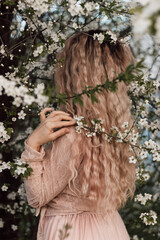A beautiful woman in a spring garden near cherry blossoms. Flowering garden