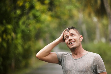 Portrait of man in wet clothes enjoying heavy rain in nature. Themes of life water, weather and environment..