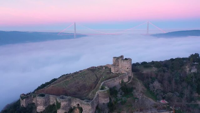 Dense fog covered the entire Bosphorus like cotton candy. Flying over Historical Yaros Castle. YSS Bridge visible with red lights in the background. Aerial view

