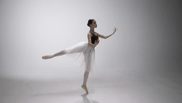 Ballerina in pointe shoes and white ballet. Classical Ballet. Girl does dance steps. Rehearsal of the part.