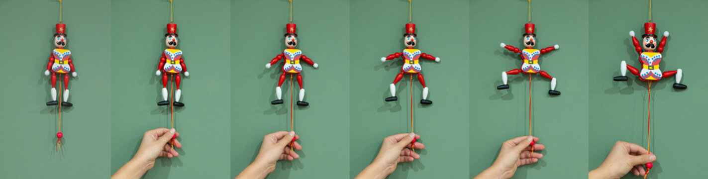 Eine Hand zieht am Spielzeug Hampelmann in die verschiedenen Positionen



