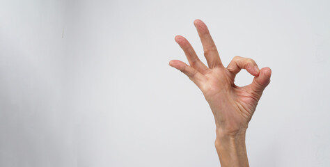 Hand of senior or older woman is doing A Ok hand sign on white background.