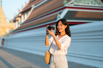 Portrait of asian woman traveler using camera at street of Bangkok, Thailand. Asia summer tourism vacation concept