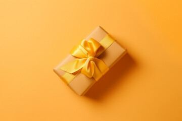 Obraz na płótnie Canvas Gift box with golden satin ribbon and bow on yellow background. Holiday gift with copy space. Birthday or Christmas present, flat lay, top view. Christmas giftbox concept. AI generated.