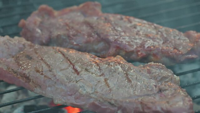Man cooking and rotating beaf steakes on grill. 4k video footage in slow motion