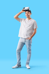 Young man using VR glasses on light blue background