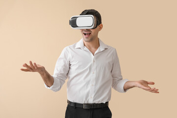 Young man using VR glasses on beige background