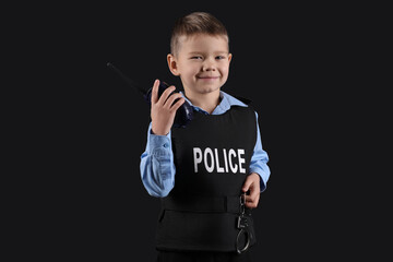 Cute little police officer with radio transmitter on black background