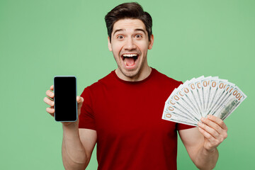 Young man wears red t-shirt casual clothes hold in hand fan of cash money in dollar banknotes...