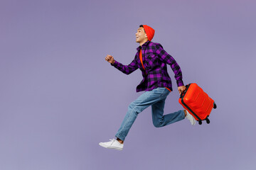 Fototapeta na wymiar Full body traveler man wear casual clothes hold suitcase isolated on plain pastel purple color background studio. Tourist travel abroad in free spare time rest getaway Air flight trip journey concept