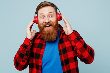 Young cheerful happy redhead bearded man he wears casual clothes headphones listen to music look...