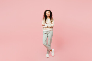 Fototapeta na wymiar Full body smiling happy cheerful young woman of African American ethnicity she wear light casual clothes hold hands crossed folded look camera isolated on plain pastel pink background studio portrait.