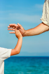 happy dad holds the hand of a child by the greek sea in nature