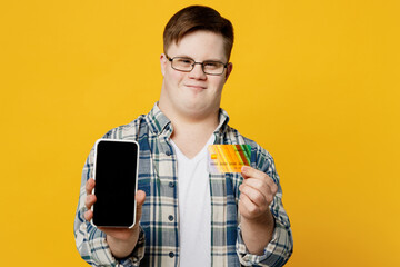 Young man with down syndrome in casual clothes glasses using mobile cell phone credit bank card...