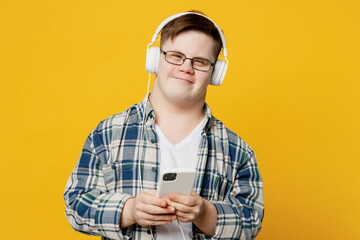 Young smiling man with down syndrome wear glasses casual clothes headphones listen to music use...