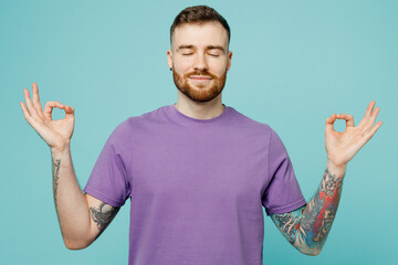 Young spiritual man he wears purple t-shirt hold spread hands in yoga om aum gesture relax meditate try to calm down isolated on plain pastel light blue cyan background Tattoo translates life is fight