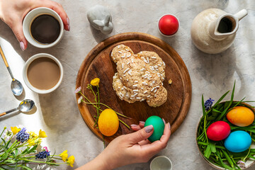 Italian Easter cake Colomba on wooden cutting board with painted eggs, easter decoration, mugs of coffee and wild flowers