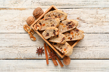 Basket with tasty biscotti cookies, spices and walnuts on light wooden background