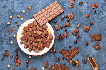 Composition with pieces of tasty chocolate, candies and nuts on color background