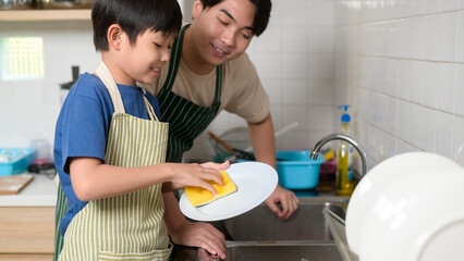 Happy smiling Young Asian father and son washing dishes in kitchen at home