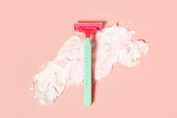 Safety razor and shaving foam on pink background