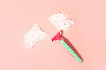 Safety razor and shaving foam on pink background