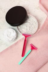 Safety razors, scrub and shaving foam on light background