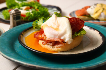 Plate with delicious egg Benedict on white wooden table, closeup