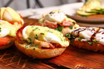 Board with different eggs Benedict on table, closeup