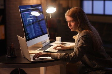 Female programmer working with laptop in office at night