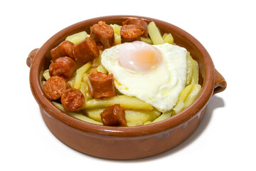 Chistorra with fried potatoes and fried eggs, served in a clay bowl (Chistorra, is a type of sausage of Navarre origin made with fresh minced pork.Isolated in a white background. Spanish food concept.