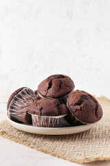 Plate with tasty chocolate cupcakes on table