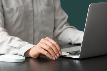 Woman using USB flash drive with modern laptop at dark table, closeup