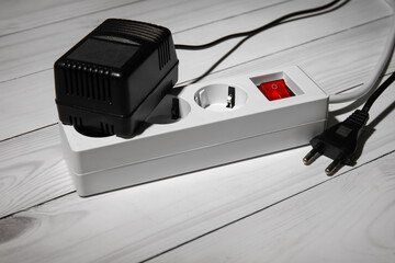 Electric extension cord with plugs on white wooden floor